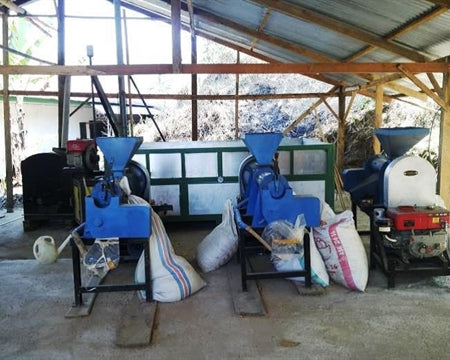 Toraja Coffee Growers Cooperative coffee farm infrastructure includes facilities such as this with coffee bagging equipment loading bags of beans.